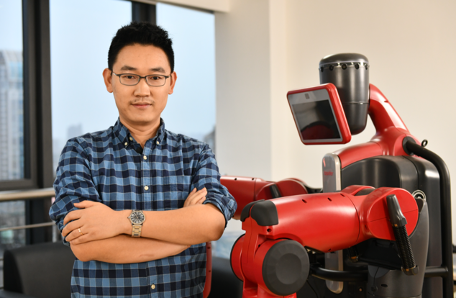 Yanwei Fu standing beside a research robot